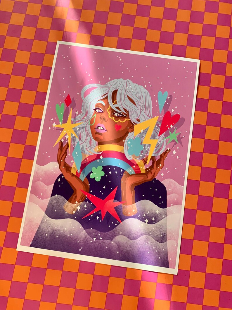 K&ouml;nnte beinhalten: Ein rechteckiger Kunstdruck mit einer stilisierten Illustration einer Person mit hellem Haar, umgeben von bunten schwebenden Elementen wie einem Regenbogen, einem gelben Blitz, Sternen, Herzen und Wolken vor einem rosafarbenen Sternenhintergrund.