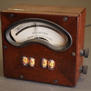 May include: A vintage ammeter in a dark wood case with a gauge and three illuminated digital displays. The gauge reads "AMIMETER GENERAL ELECTRIC CO. U.S.A." and has a curved needle. Two knobs are on the right side.