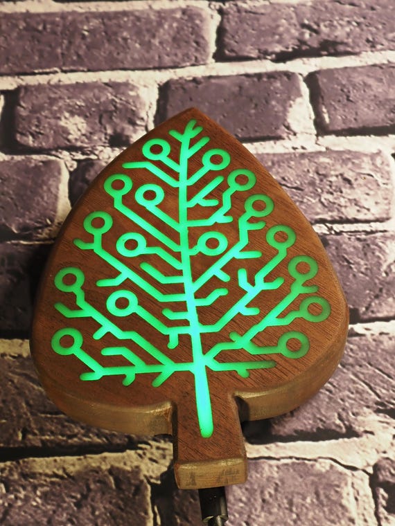 Walnut wood meets glowing green epoxy circuit board inlay with LED backlighting — it's genuinely striking wall art that looks like it came from a sci-fi movie prop department.