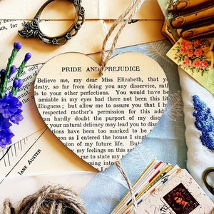 May include: A heart-shaped wooden ornament featuring a printed page from the book "Pride and Prejudice" by Jane Austen. The text reads "Believe me, my dear Miss Elizabeth, that you..."