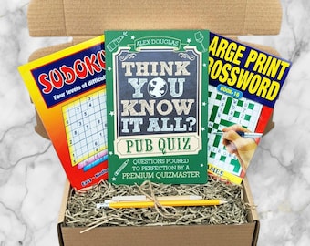 Può includere: Una scatola di cartone piena di un libro di quiz da pub, un libro di Sudoku e un libro di cruciverba a stampa grande. Una matita gialla poggia sulla carta sminuzzata all'interno della scatola. Il libro dei quiz da pub dice "Think You Know It All?"