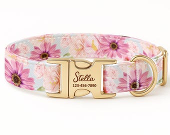 May include: A pet collar featuring a light blue background with a pink floral pattern. The collar includes a gold-toned metal side-release buckle engraved with the name Stella and the phone number 123-456-7890, along with a matching gold D-ring.