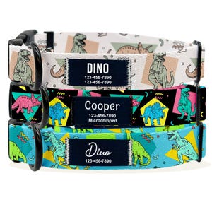 May include: Three dog collars with dinosaur patterns. The top collar is white with brown dinosaurs and the text "DINO 123-456-7890 123-456-7890". The middle collar is black with pink, blue, and yellow dinosaurs and the text "Cooper 123-456-7890 Microchipped". The bottom collar is blue with green and yellow dinosaurs and the text "Dino 123-456-7890".