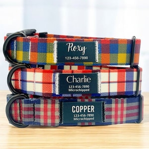 May include: Three dog collars with plaid patterns in red, blue and yellow. Each collar has a black tag with a name, phone number and the text "Microchipped". The names on the tags are Roxy, Charlie and Copper.
