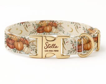 Könnte beinhalten: Ein cremefarbenes Hundehalsband mit einem herbstlichen Kürbismuster. Die goldfarbene Schnalle trägt den Namen "Stella" und eine Telefonnummer. Das Halsband ist für Haustiere konzipiert und hat einen D-Ring zur Befestigung der Leine.