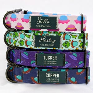 May include: Four colorful dog collars with a space theme. Each collar has a black label with a name and phone number. The names are Stella, Harley, Tucker, and Copper. The collars are pink, green, purple, and blue.