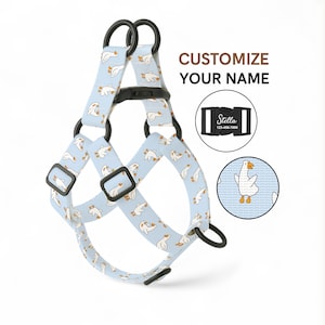 May include: A light blue dog harness featuring a pattern of white geese. The harness has black buckles and rings. The text "CUSTOMIZE YOUR NAME" is displayed. A small, circular image shows a goose.