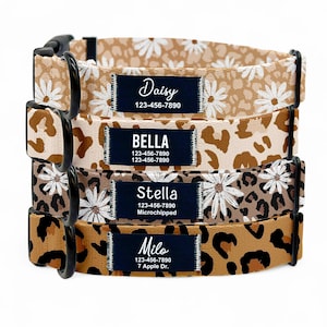 May include: Four dog collars with personalized name tags. The collars are brown with a leopard print and white daisy pattern. The name tags are black with white text. The names on the tags are Daisy, Bella, Stella, and Milo.