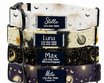 May include: Four dog collars with celestial patterns. The collars are stacked on top of each other. The top collar is white with gold stars and moons. The second collar is beige with gold stars and a planet. The third collar is black with gold stars and moons. The bottom collar is purple with gold stars and moons. Each collar has a black tag with white text that includes a name, phone number, and optional address.