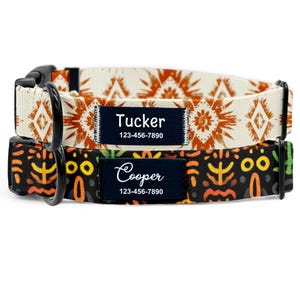 Puede incluir: Dos collares personalizados para perros. El collar superior es de color crema con un patrón geométrico naranja. El collar inferior es negro con un diseño tribal colorido. Cada collar tiene una etiqueta con el nombre azul marino con un nombre y número de teléfono.