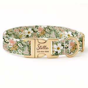 May include: A floral dog collar with a gold-colored buckle and D-ring. The collar features a pattern of white, pink, and yellow flowers on a green background. The buckle is engraved with the name "Stella" and a phone number.