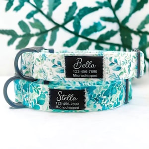 Könnte beinhalten: Zwei Hundehalsbänder mit weißem Hintergrund und einem blaugrünen Blumenmuster. Die Halsbänder haben schwarze Schnallen und schwarze Namensschilder mit weißem Text. Das obere Halsband trägt den Namen "Bella" und die Telefonnummer "123-456-7890". Das untere Halsband trägt den Namen "Stella" und die Telefonnummer "123-456-7890". Beide Halsbänder haben den Schriftzug "Mikrogechipt" auf den Schildern.