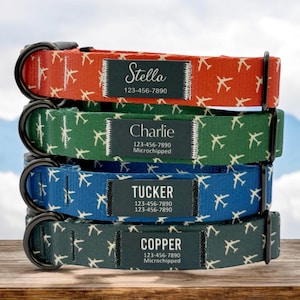 May include: Four dog collars stacked on top of each other. The collars are made of red, green, blue, and dark green fabric with a white airplane pattern. Each collar has a black tag with white text that includes a name, phone number, and "Microchipped" for some collars.