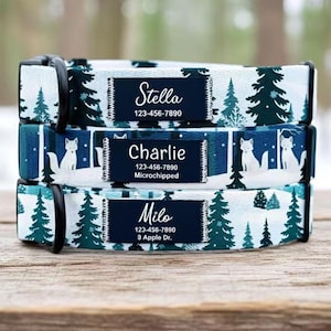 May include: Three personalized dog collars stacked on top of each other. Each collar has a navy blue tag with a white name and phone number. The collars have a winter forest pattern with evergreen trees and foxes.
