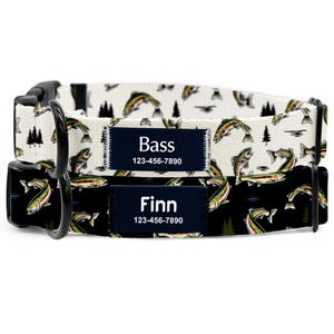 May include: Two dog collars with a fishing theme. One collar is white with a pattern of fish and trees, the other is black with a similar pattern. Each collar has a navy blue patch with a name and phone number.