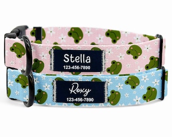 May include: Two personalized dog collars. One is light pink with a frog and flower pattern, the other is light blue with the same pattern. Each collar has a black buckle and a name tag that reads "Stella" and "Roxy" with a phone number.