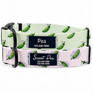 Könnte beinhalten: Zwei Hundehalsbänder mit schwarzen Verschlüssen. Eines ist hellgrün mit grünen Erbsenschoten-Grafiken, das andere ist hellrosa mit Erbsenschoten-Grafiken. Jedes Halsband hat ein marineblaues Etikett mit dem Namen "Pea" oder "Sweet Pea" und einer Telefonnummer.