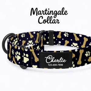 Può includere: Un collare Martingale nero per cani con un motivo di ossa e impronte di zampe beige. Il collare ha un'etichetta nera con il nome "Charlie" e un numero di telefono. Il collare ha finiture in metallo nero.