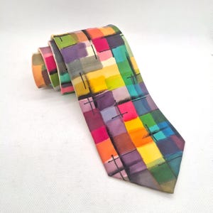May include: A necktie featuring a vibrant, multi-colored grid pattern of painted squares in shades of yellow, orange, pink, purple, green, and blue. The design includes thin, black, hand-drawn style lines that intersect across the colorful blocks.