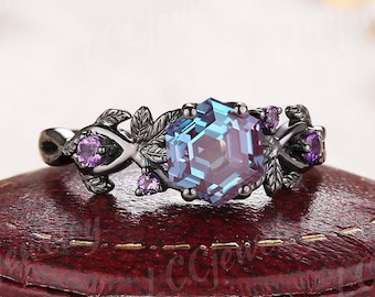 May include: Black ring with a large hexagonal blue and purple gemstone surrounded by smaller purple gemstones and a leaf design.