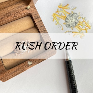 May include: A wooden ring box with a ring inside, a pencil, and a drawing of a ring design on a white sheet of paper. The text "RUSH ORDER" is written across the top of the image.