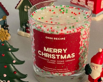 May include: A clear glass candle filled with white wax topped with red, green, and white sprinkles. The red label reads ONNI RECIPE MERRY CHRISTMAS GINGERBREAD ANISE COOKIE CINNAMON CARAMEL VANILLA Rapeseed wax candle | 55 h Hand poured in the Netherlands.