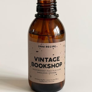 May include: A brown glass bottle diffuser with wooden reeds. The label reads "VINTAGE BOOKSHOP" with scent notes. The bottle is filled with a rapeseed blend and hand-poured. The diffuser is designed for home fragrance.