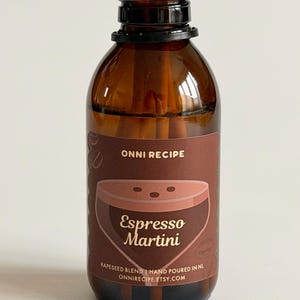 Puede incluir: Un difusor de aromaterapia de vidrio marrón con tapa negra y varillas de madera. La etiqueta dice "ONNI RECIPE Espresso Martini" con un gráfico de cóctel. Contiene una mezcla de colza, vertida a mano en los Países Bajos.