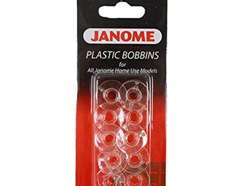 May include: A package of clear plastic bobbins for Janome sewing machines. The package has a black top with a white and red label that reads "JANOME PLASTIC BOBBINS". The bobbins are visible through a clear plastic window.