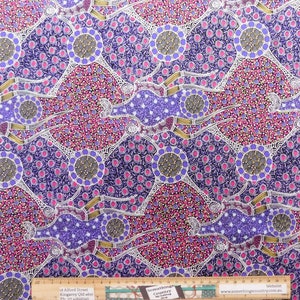 May include: Purple and pink fabric with a repeating pattern of stylised figures and circles. The fabric has a white background with gold accents. The fabric is printed with the text "Somethings Country" and a website address.