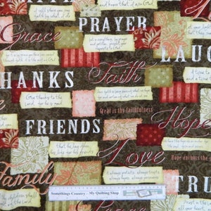 May include: A brown fabric with a patchwork design featuring various words and phrases related to faith, love, and hope. The words are printed in white, red, and cream on a brown background. The fabric is decorated with floral patterns in shades of cream and pink.