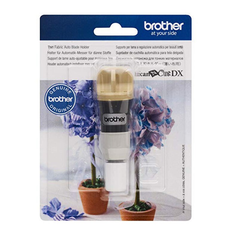 Op de afbeelding: Een Brother Thin Fabric Auto Blade Holder in een transparante plastic verpakking. De houder is beige, zwart en wit. De verpakking bevat tekst in meerdere talen, waaronder "Genuine Brother Original."