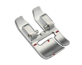 May include: Silver sewing machine foot with red markings. The foot has a small opening in the center and two prongs on either side.