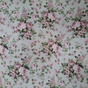 May include: Fabric featuring a floral pattern of pink roses and smaller flowers on a pale blue backdrop. Green leaves and stems are woven throughout the design, creating a classic, romantic aesthetic.