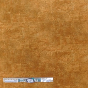 May include: A close-up of a textured fabric in a warm brown colour. The fabric has a subtle sheen and a slightly rough texture. The fabric is perfect for quilting, crafts, and home decor projects.
