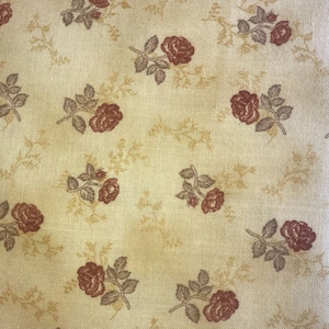 May include: Cream-coloured fabric featuring a repeating pattern of burgundy roses and muted green leaves. Delicate, light brown floral vines are scattered across the background. The fabric has a slightly textured appearance.