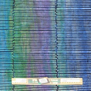 May include: A blue, green and purple batik fabric with a horizontal stripe pattern. The fabric is measured with a ruler.