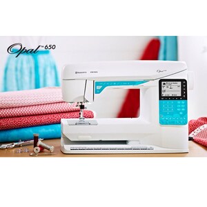 May include: A white Husqvarna Viking Opal 650 sewing machine with a digital display and teal detailing. The machine is on a wooden surface, with spools of thread and fabric visible.