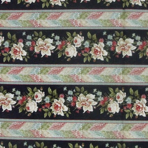 May include: Black fabric with a repeating pattern of white roses and green leaves. The fabric has a striped design with alternating bands of black, white and pink.