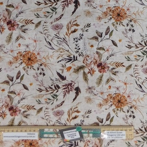 May include: A beige fabric with a floral pattern featuring various shades of brown, orange, and pink flowers. The fabric has a subtle linen texture and is perfect for crafting projects.