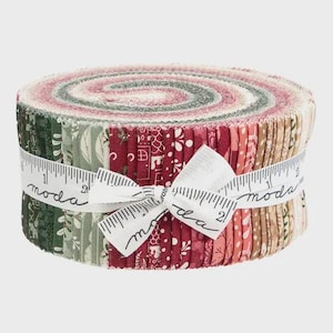 May include: A rolled bundle of fabric strips in shades of red, green, and beige, tied with a white ribbon printed with "moda" and a measuring tape design. The fabric features floral and geometric patterns.