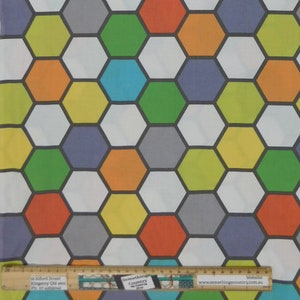 May include: A white fabric with a repeating pattern of colourful hexagons. The hexagons are in shades of orange, yellow, green, blue, and grey. The fabric is for sale at Something Country, a shop located at 18 Alford Street, Kingaroy Qld 4610, Australia. Their website is www.somethingscountry.com.au.