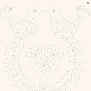May include: A light cream-colored fabric panel featuring a delicate, light gray dashed-line embroidery pattern. The design depicts two facing birds positioned above a central heart shape, which is filled with three floral motifs, all framed by leaves.