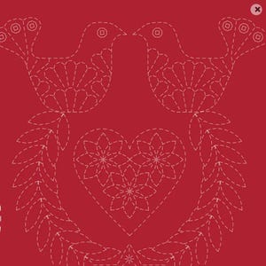 Peut inclure: Un tissu rouge profond présentant un motif brodé blanc de deux oiseaux se faisant face au-dessus d'un cœur central. Le cœur est composé de trois motifs floraux, et l'ensemble du design est encadré par deux branches feuillues blanches.