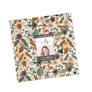 May include: A square stack of fabric squares featuring a floral pattern with cream, sage green, dusty pink, and dark brown colours. A label on the front displays the text "moda", "SUNLIT RAINS", "by JESSICA ROSE", and "moda FABRICS + SUPPLIES" with a 12.7 cm ruler.