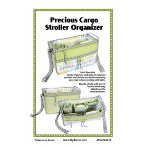 May include: A green and black stroller organiser with multiple pockets and zippered compartments. The organiser has a printed fabric with the words "Giraffe", "Elephant", "Zebra", "Lion", and "Raffia". The text "Precious Cargo Stroller Organiser" is printed at the top of the image. The text "Patterns by Annie www.ByAnnie.com 435-674-9816" is printed at the bottom of the image.