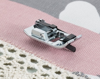 May include: A silver sewing machine foot with a black plastic adjustment lever. The foot is designed for sewing on delicate fabrics.