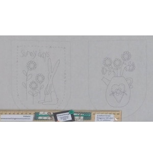 Könnte beinhalten: Zwei Stickmuster auf weißem Stoff. Das erste Muster zeigt ein Kaninchen und Sonnenblumen mit dem Text "Sunny days". Das zweite Muster zeigt eine Vase mit einem Herzen und Blumen.