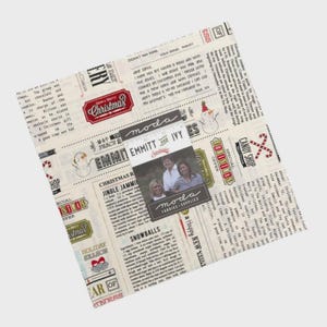 May include: A square stack of fabric squares featuring a vintage newspaper print with Christmas-themed text, illustrations of snowmen, and candy canes. A central label displays the text Moda, Emmitt and Ivy, and a photograph of three people.