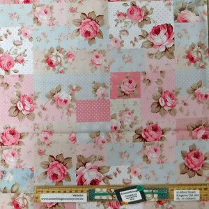 May include: A patchwork fabric featuring a repeating pattern of pink roses with green leaves on a background of pink, blue and beige squares with white polka dots. The fabric is 80 inches wide. The text "Somethings Country" and a website address are visible in the image.